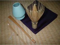 A set of implements for the Japanese tea ceremony.  From bottom left: chashaku (tea scoop), sensu (fan), whisk shaper, chasen (bamboo whisk) and fukusa (purple silk cloth)